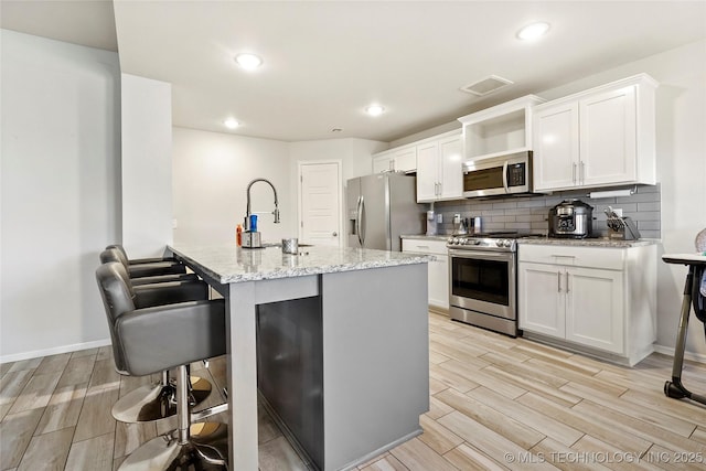 kitchen with stainless steel appliances, light stone countertops, sink, and white cabinets