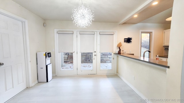 kitchen with hanging light fixtures, white cabinets, a notable chandelier, and sink