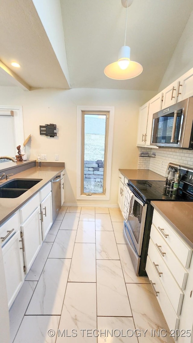 kitchen featuring backsplash, sink, white cabinetry, hanging light fixtures, and stainless steel appliances