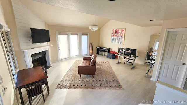 living room featuring light hardwood / wood-style floors, a large fireplace, a textured ceiling, and vaulted ceiling