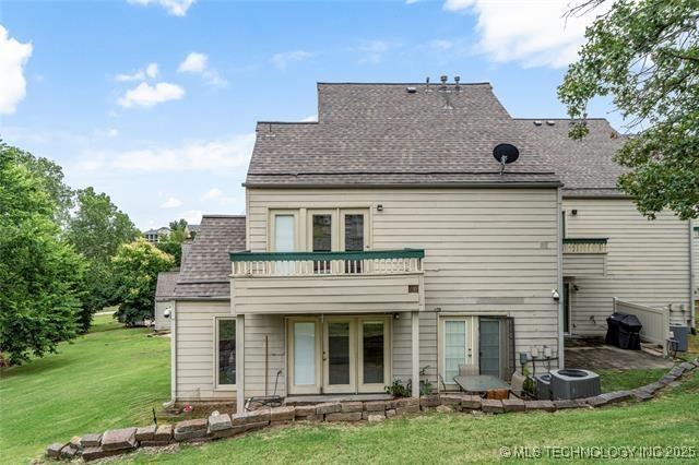 back of house with central AC, a lawn, and a balcony