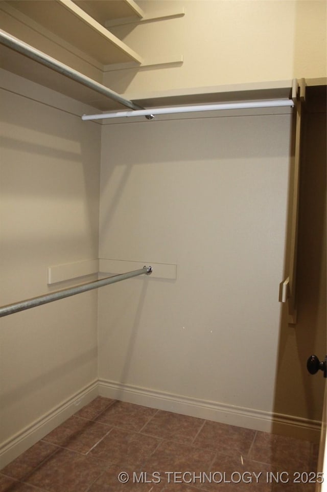 walk in closet featuring dark tile patterned flooring