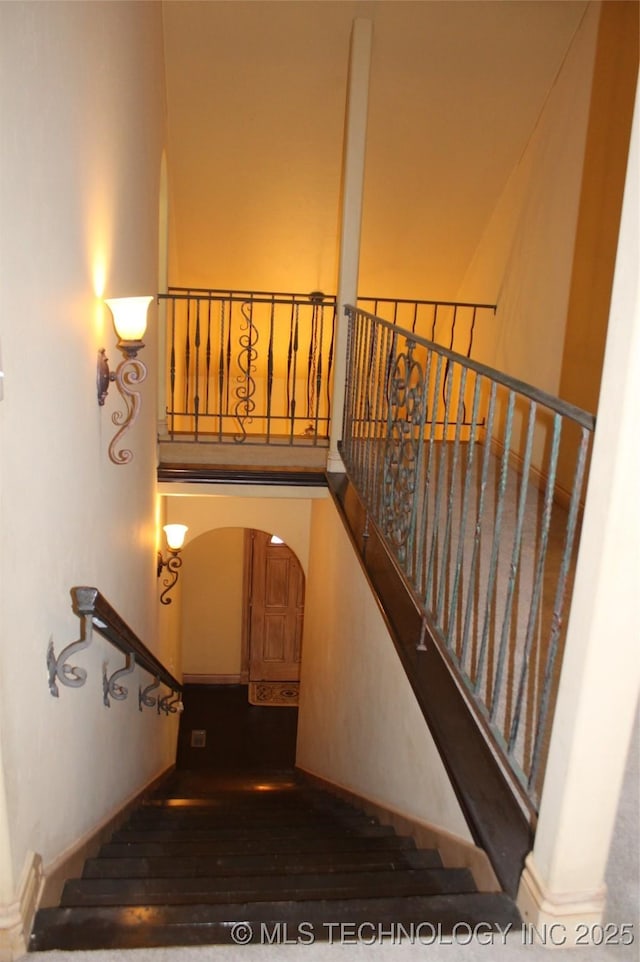 staircase with wood-type flooring and a towering ceiling