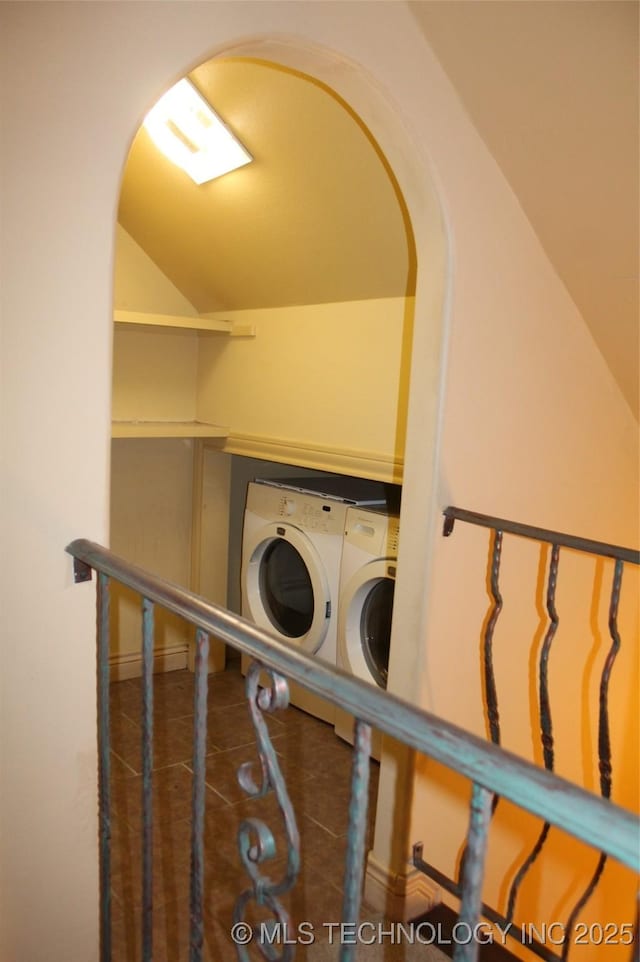 clothes washing area featuring dark tile patterned floors and washing machine and dryer