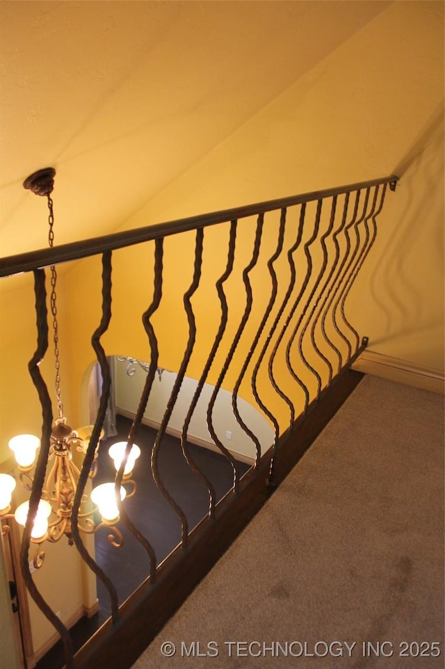 stairway with a chandelier and carpet flooring