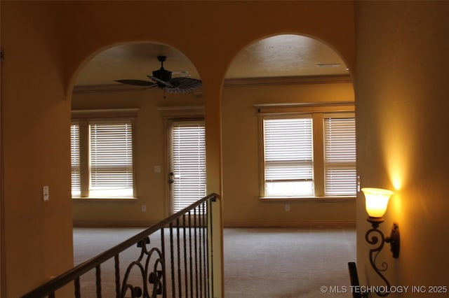 corridor featuring ornamental molding, light colored carpet, and plenty of natural light