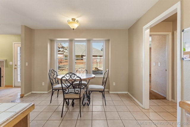 dining space featuring light tile patterned floors and a tiled fireplace