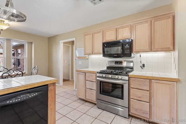 kitchen featuring backsplash, black appliances, tile counters, light tile patterned floors, and light brown cabinetry