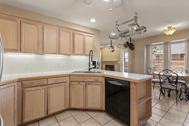 kitchen with tile countertops, kitchen peninsula, tasteful backsplash, dishwasher, and sink