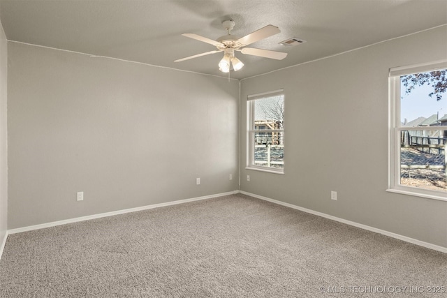 empty room with ceiling fan, plenty of natural light, and carpet floors