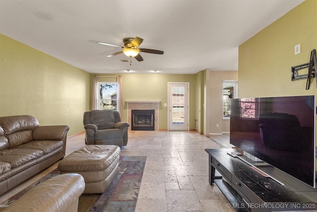 living room featuring ceiling fan and a tiled fireplace