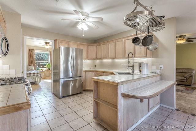 kitchen with sink, stainless steel fridge, kitchen peninsula, and tile countertops