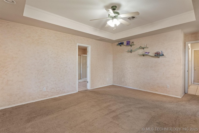 empty room with a raised ceiling, carpet floors, and ornamental molding