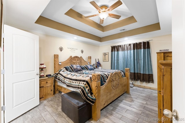 bedroom with ceiling fan, a tray ceiling, light hardwood / wood-style flooring, and ornamental molding