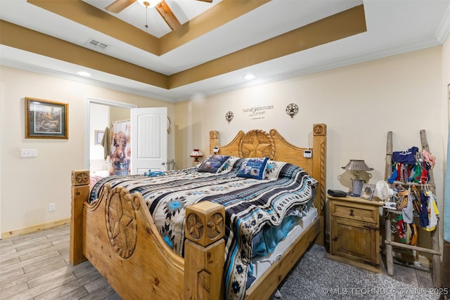 bedroom featuring ceiling fan, crown molding, a raised ceiling, and light wood-type flooring