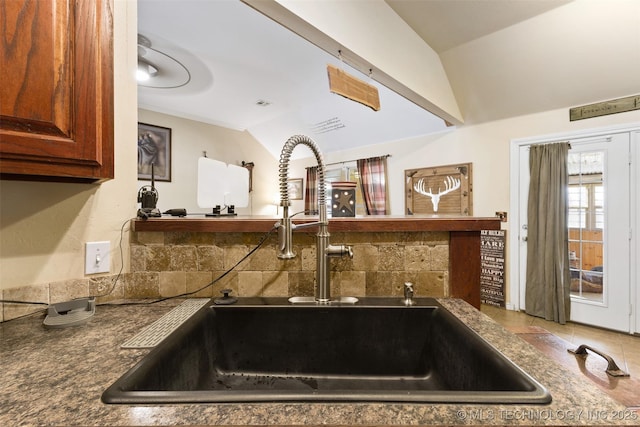 kitchen featuring vaulted ceiling, sink, and decorative backsplash