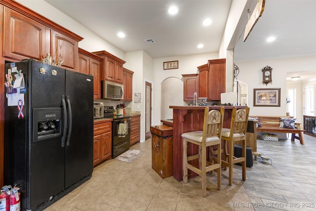 kitchen with a kitchen breakfast bar, black appliances, and sink