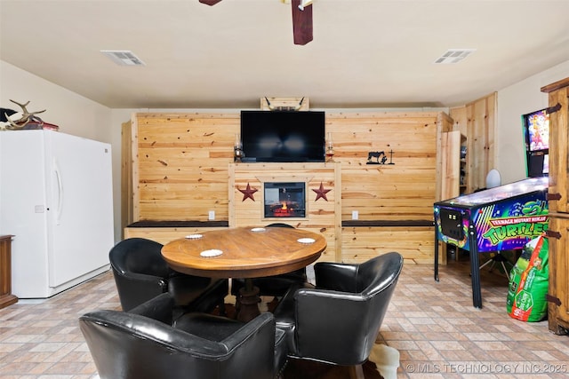 game room featuring ceiling fan and wood walls