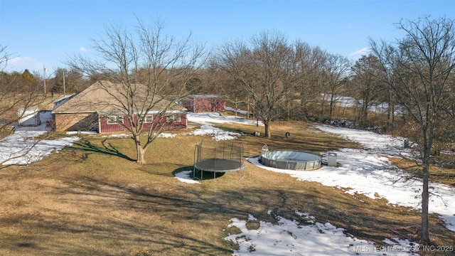 yard layered in snow with a covered pool and a trampoline