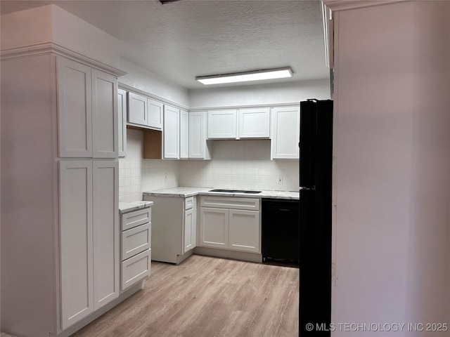 kitchen with a textured ceiling, white cabinets, black appliances, light hardwood / wood-style floors, and backsplash