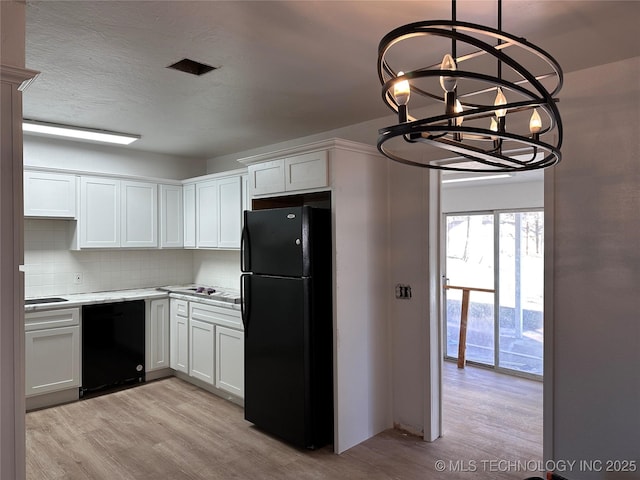 kitchen with tasteful backsplash, pendant lighting, black appliances, white cabinets, and a chandelier