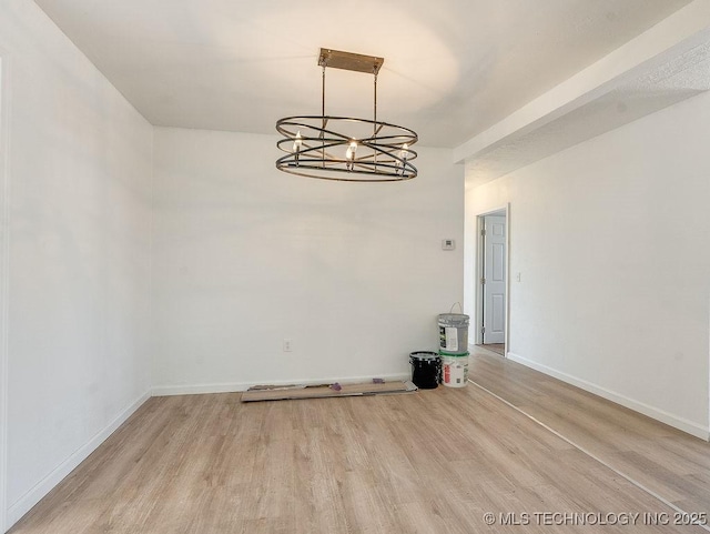 unfurnished dining area with a chandelier and light hardwood / wood-style floors