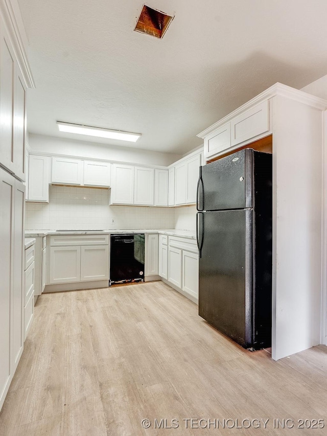 kitchen featuring white cabinetry, backsplash, light hardwood / wood-style floors, and black appliances