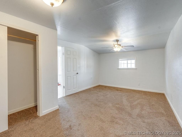 basement with ceiling fan, carpet flooring, and a textured ceiling