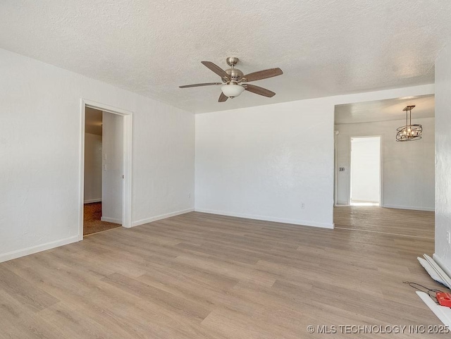 unfurnished room with ceiling fan with notable chandelier, a textured ceiling, and light wood-type flooring