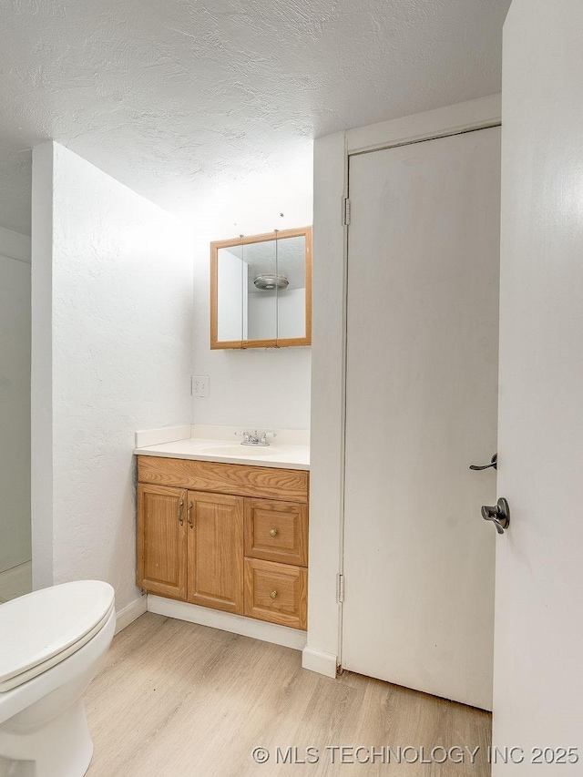 bathroom featuring wood-type flooring, vanity, a textured ceiling, and toilet