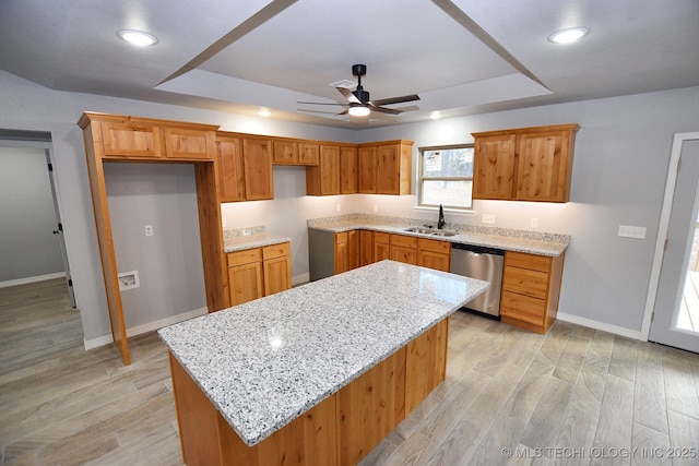 kitchen with ceiling fan, dishwasher, a kitchen island, sink, and light stone countertops