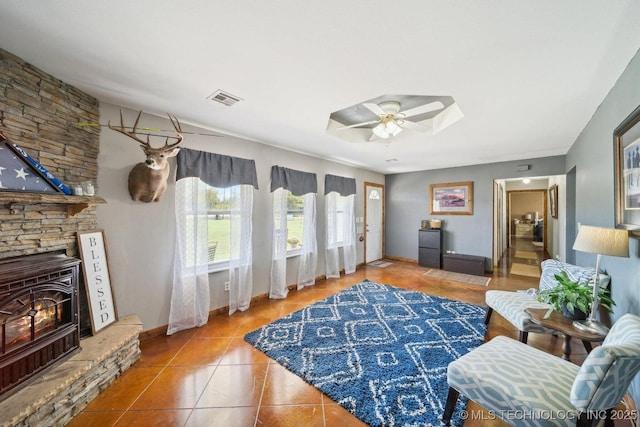 tiled living room with ceiling fan and a wood stove