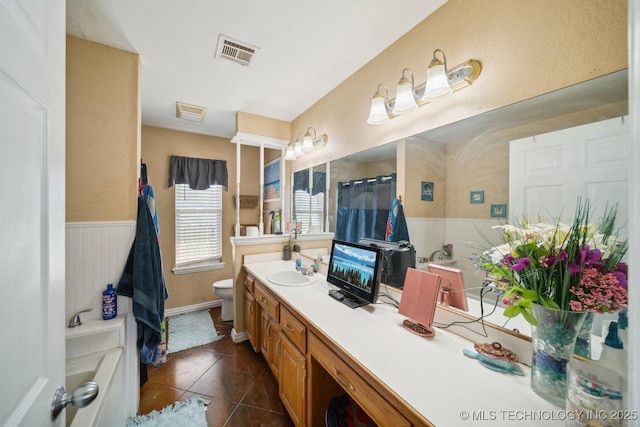 bathroom with toilet, vanity, and tile patterned flooring