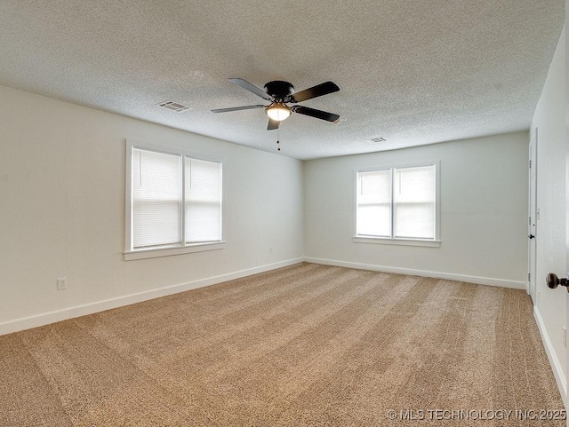 carpeted empty room with ceiling fan, a healthy amount of sunlight, and a textured ceiling