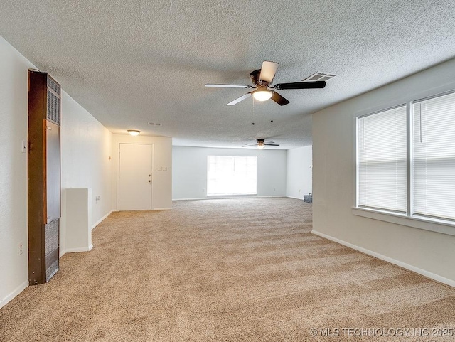 carpeted empty room featuring ceiling fan, a textured ceiling, and a healthy amount of sunlight