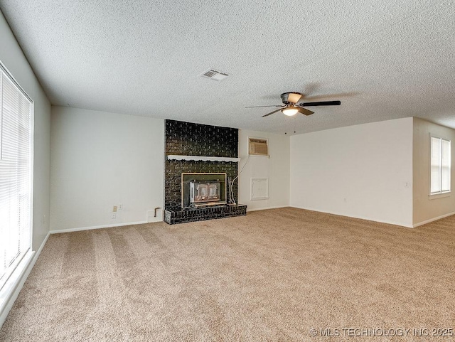 unfurnished living room with carpet, ceiling fan, a fireplace, a wall mounted air conditioner, and a textured ceiling