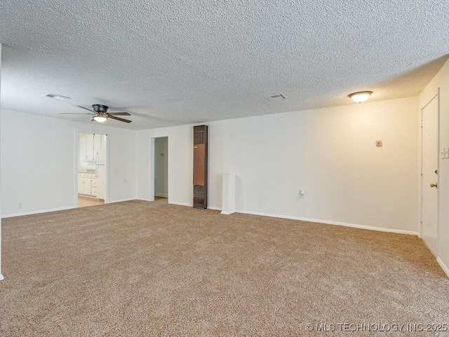 spare room with ceiling fan, a textured ceiling, and light carpet