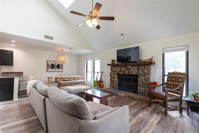 living room with high vaulted ceiling, a healthy amount of sunlight, a fireplace, and hardwood / wood-style flooring