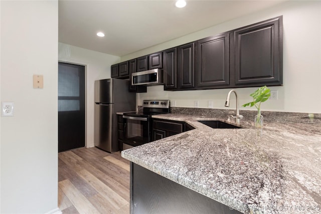 kitchen featuring light stone counters, sink, light hardwood / wood-style flooring, and stainless steel appliances