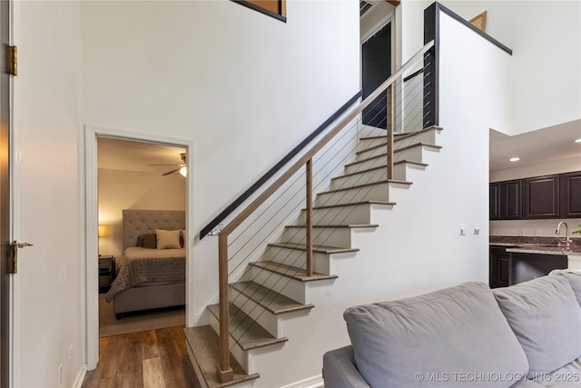 staircase with hardwood / wood-style floors and a towering ceiling