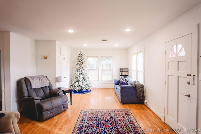 living room with light wood-type flooring and crown molding