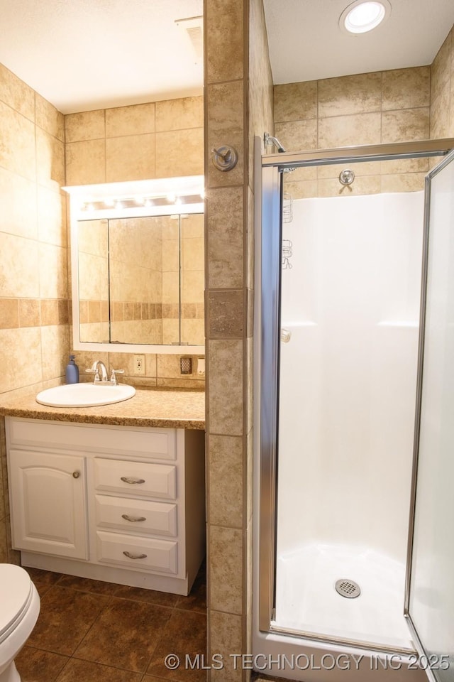 bathroom with a shower with shower door, tile walls, toilet, and vanity