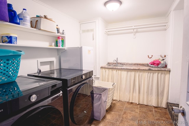 washroom with ornamental molding, washing machine and clothes dryer, and sink