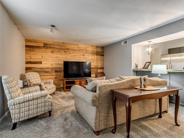 living room with an inviting chandelier, carpet, and wood walls