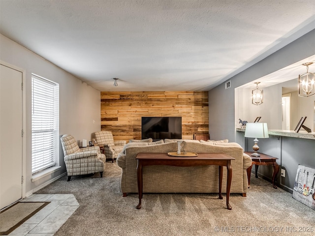 carpeted living room featuring plenty of natural light, wooden walls, and a chandelier