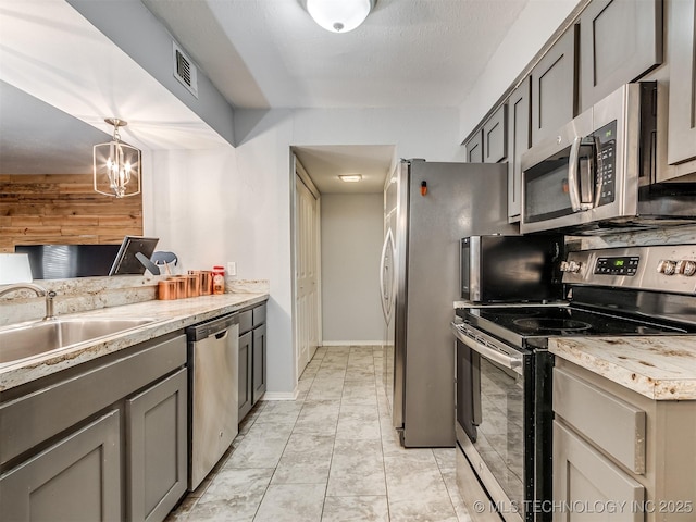 kitchen featuring an inviting chandelier, gray cabinets, stainless steel appliances, hanging light fixtures, and sink