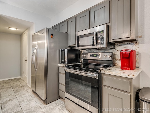 kitchen featuring backsplash, gray cabinetry, stainless steel appliances, a textured ceiling, and light tile patterned floors