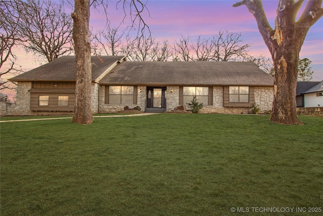 view of front facade featuring stone siding and a lawn