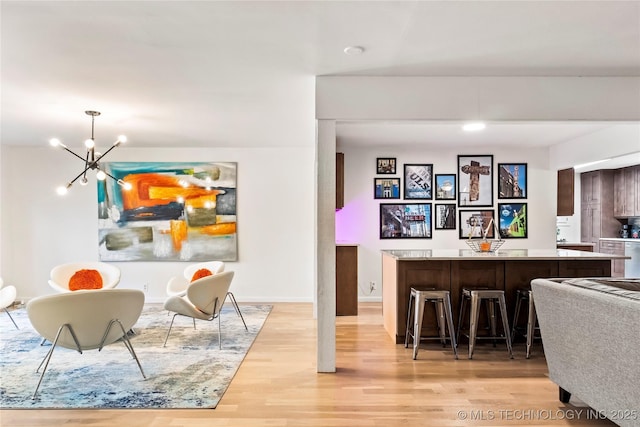 interior space featuring indoor bar, a notable chandelier, hanging light fixtures, light wood-type flooring, and baseboards