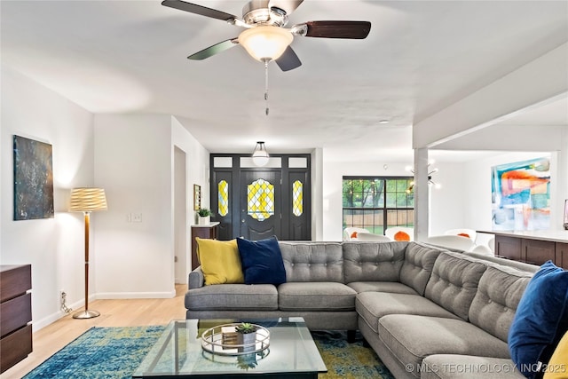 living area featuring light wood-type flooring, baseboards, and a ceiling fan